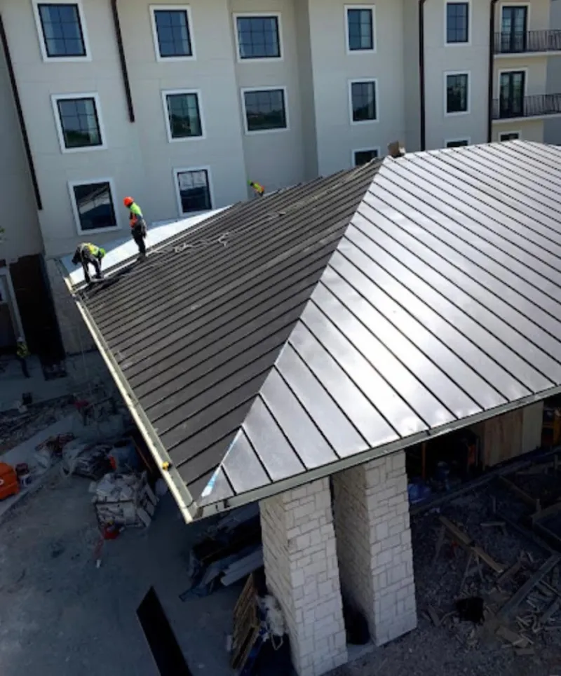 Crew installing standing seam metal roof panels on a commercial project in Southern Pines
